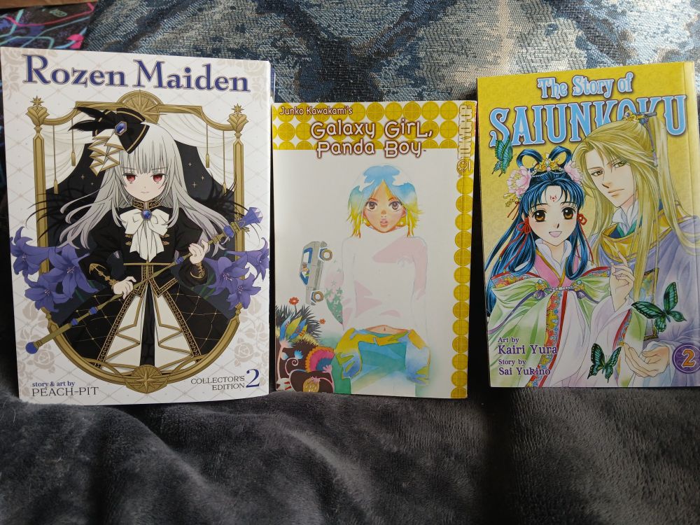 A photo of three volumes of manga. From left to right, they are volume 2 of Rozen Maiden by Peach-Pit, Galaxy Girl, Panda Boy by Junko Kawakami, and volume 2 of The Story of Saiunkoku by Sai Yukino and Kairi Yura.