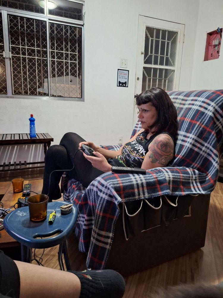 mulher sentada numa poltrona, com um controle de videogame nas mãos