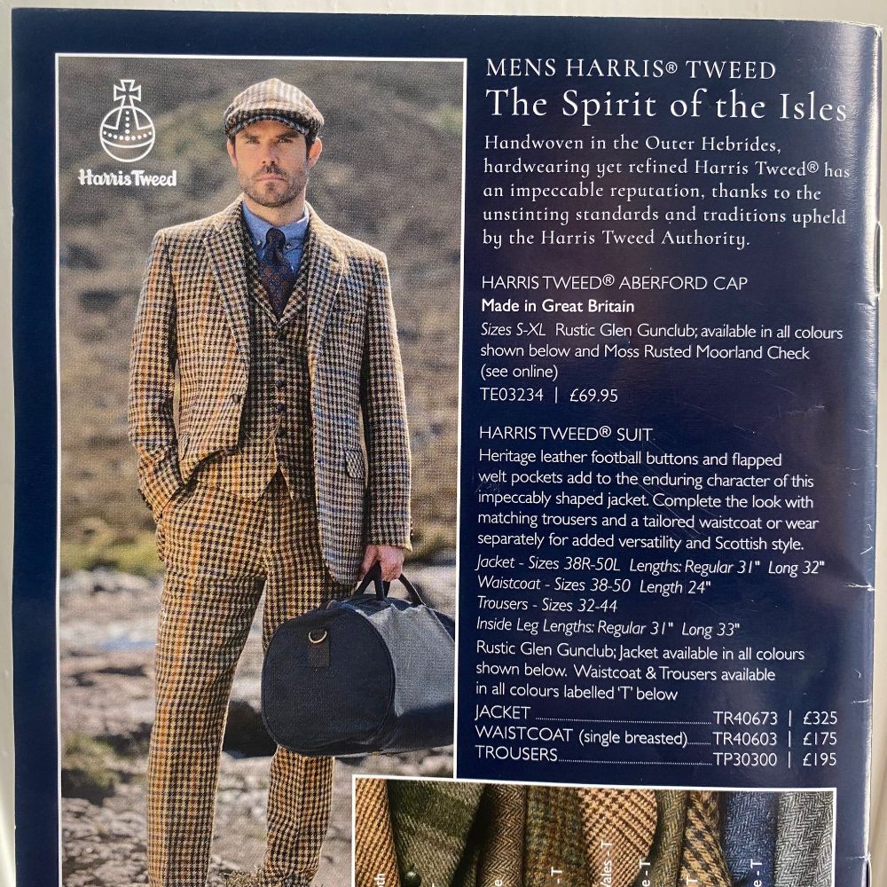 A man in a three-piece tweed suit and tweed cap stands by a river on moorland. He is holding a small travel bag and looks serious to the point of annoyed. The bag doesn't look heavy.