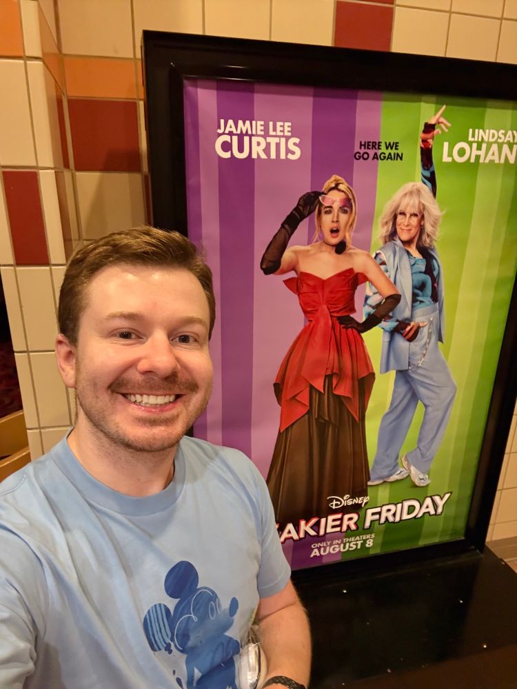 A photo of me in front of a Freakier Friday poster at the movie theater.