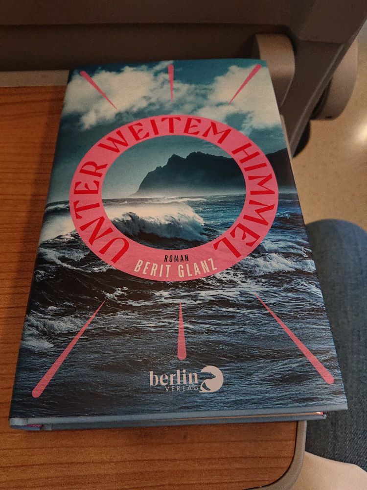 Buch auf einer Ablage im Zug: Unter weitem Himmel von Berit Glanz