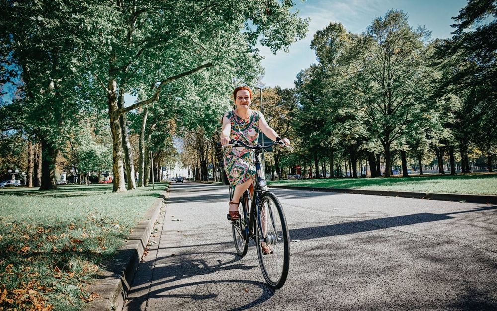 I Katja Dörner auf dem Fahrrad auf einem Weg zwischen Bäumen.