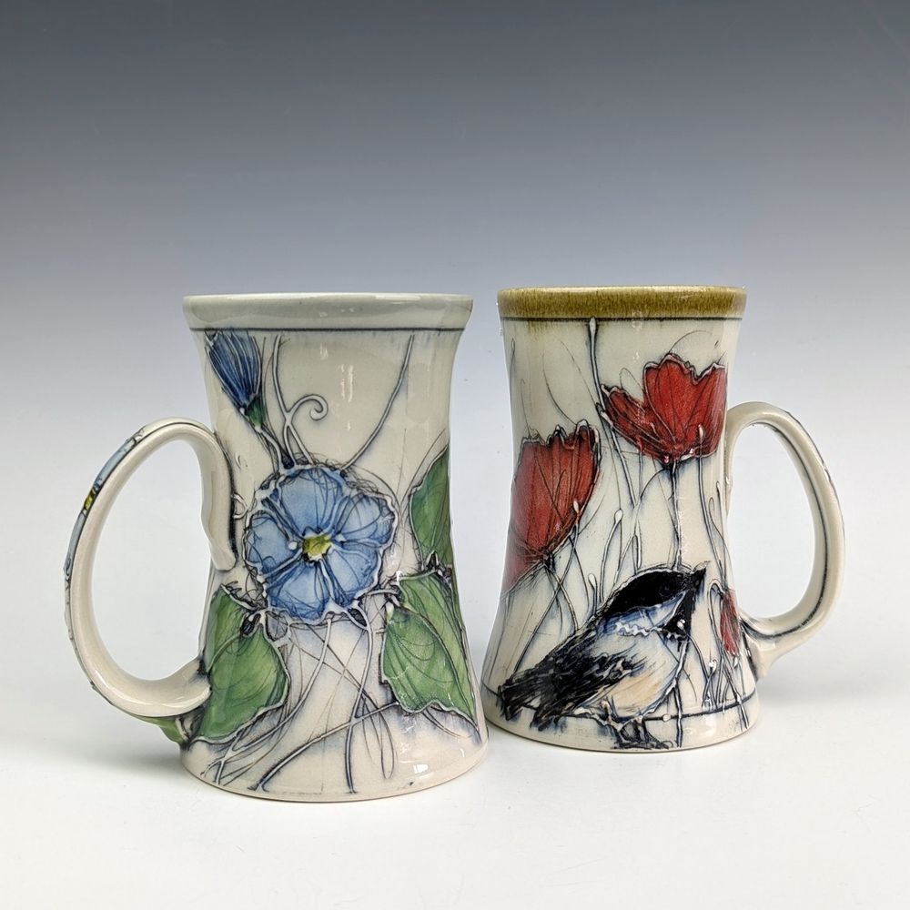 Two tall pottery mugs with floral and chickadee imagery