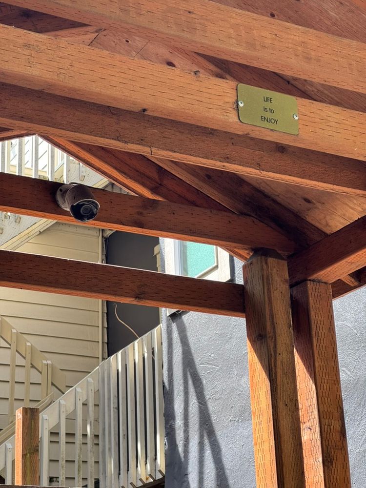 Roofed gate, featuring a plaque reading 'LIFE IS TO ENJOY' while a security camera operates in the background