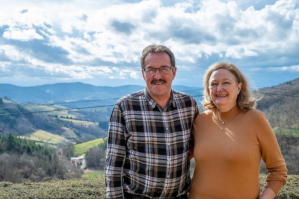 Photo de Christine et Serge à l'extérieur, devant un paysage valloné