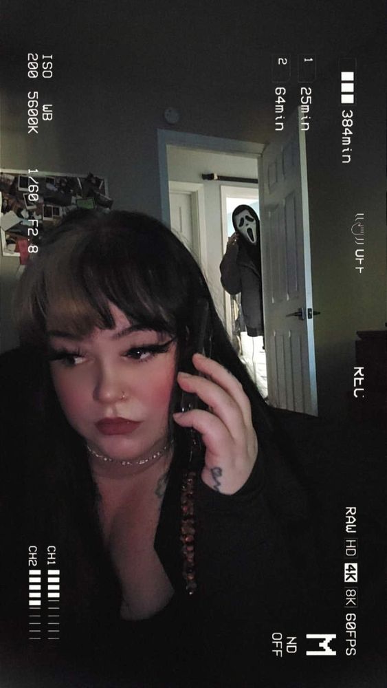 I'm looking off screen, with my phone to my ear while someone in a ghost face mask looks in the door behind me