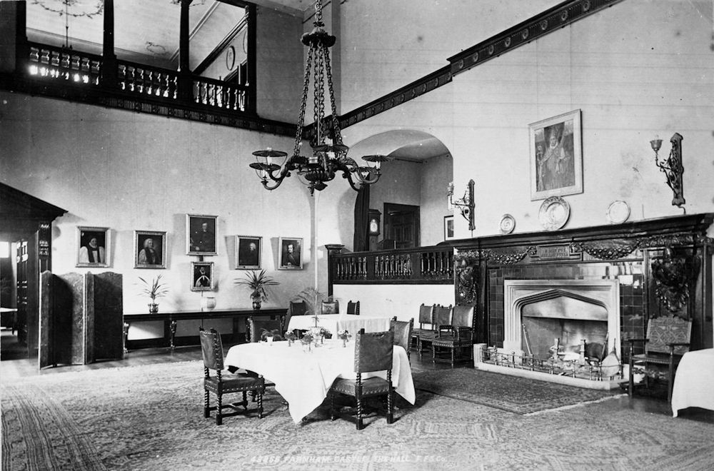 Black and white photo of the Great Hall with a table laid up in the centre