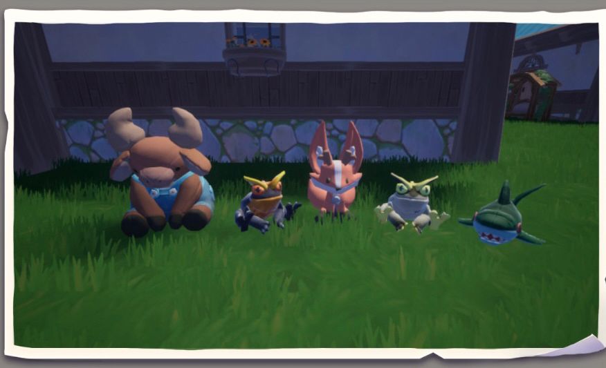 A photo of five plushies from the game Palia. From left to right there is a brown cow in overalls, a frog, a kitsuu which is a fox like creature, another frog in a lighter shade, and then a dark green shark.