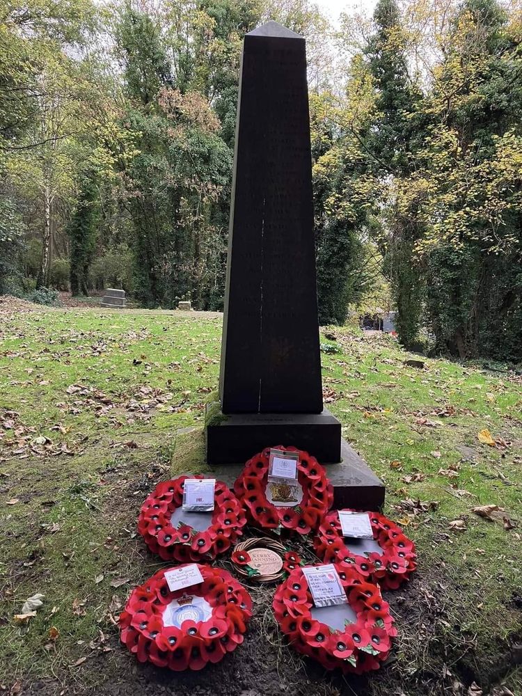 The neatly cut grass on the chapel site with poppy wreaths laid at the base of the obelisk memorial.