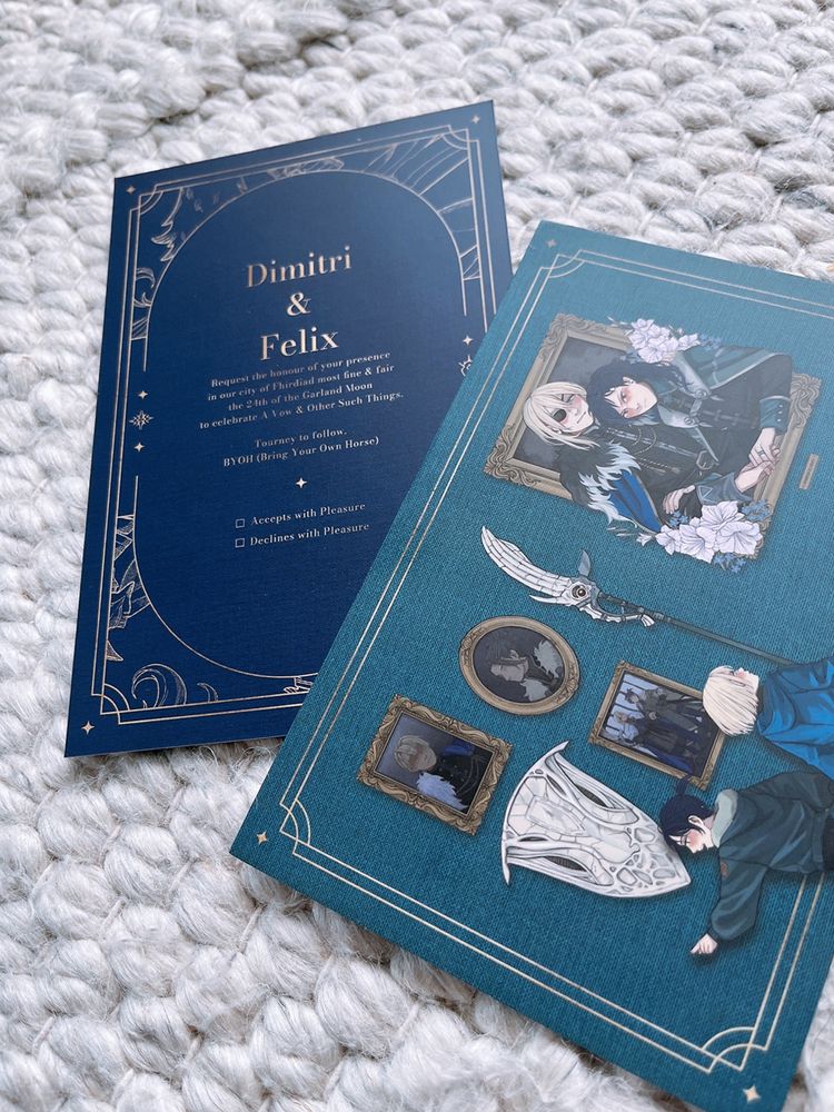 Two wedding invites, so the front and back can be seen together. 

One side is royal blue with a fanciful gold border with the Blaiddyd and Fraldarius crests, and is the invite itself; it reads in gold font: "Dimitri & Felix request the honour of your presence in our city of Fhirdiad most fine & fair the 24th of the Garland Moon to celebrate A Vow & Other Such Things. Tourney to follow. BYOH (Bring Your Own Horse)". Two checkboxes follow with the options of "Accepts with Pleasure" and "Declines with Pleasure". 

The other side is teal green and the full cover art can be seen: child Felix, with a cute little pokey ponytail, and child Dimitri, with his chin-length pageboy hair, are in modern day winter jackets in their respective teal and blue colours, and are running across a museum hall where various paintings of canon Dimitri and Felix are hung on the wall, along with Areadbhar and the Aegis shield. Child Felix has child Dimitri's hand in a death grip, grinning brightly and looking back while a very serious looking child Dimitri is looking forward at the large portrait hung in front of them. It's of a smiling post-canon Dimitri and a happy frowning post-canon Felix in formal outfits, Dimitri's inspired by his fur cloak and Felix's inspired by his ducal outfit. They're sitting inside a large picture frame, as if in royal portrait, but their hands are laid together on top of the bottom frame. Felix wears a very visible ring with a blue stone on his finger. White gladioli and blue forget-me-not flowers spill all round them. It's like neither men, nor flower, nor their joy can be contained within the picture frame.