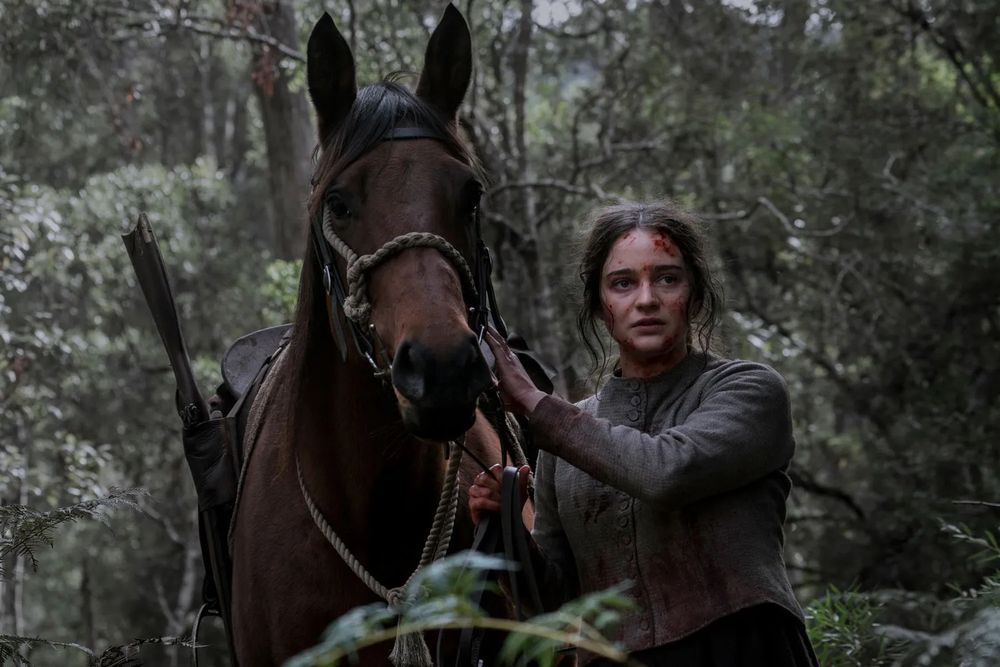 Clare (Aisling Franciosi) walks beside a horse through the Tasmanian forest in a scene from THE NIGHTINGALE.