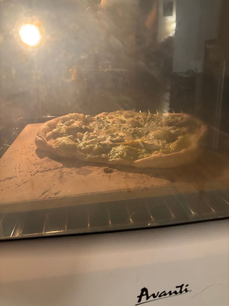 Pizza on a baking stone in an oven
