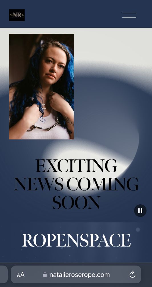 A screenshot of the website for Ropenspace at Natalieroserope.com , featuring a picture of Ron Swanson in a white tank and leather harness, with long curly blue hair. The text reads "exciting news coming soon."