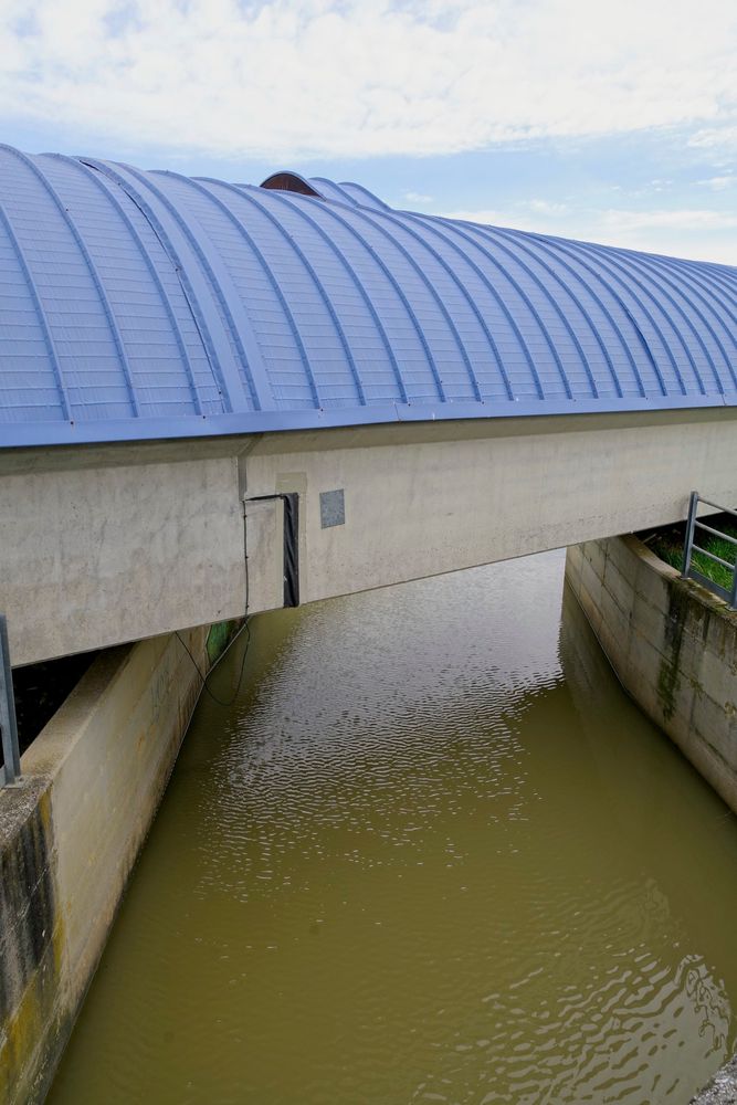 Vue extérieure d'un bras de Virgo au dessus d'un canal en eau.