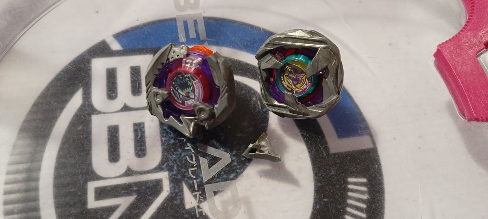 Samurai caliber beyblade next to a broken shark edge beyblade 