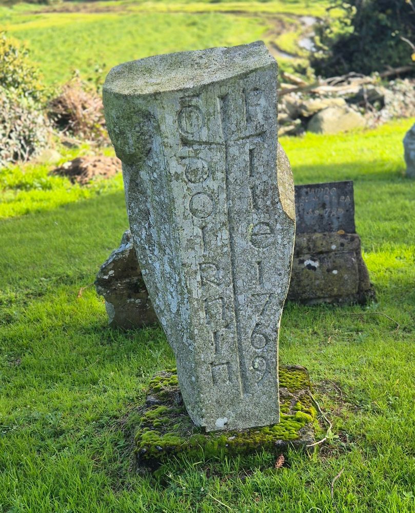 Green grass and a 17th century burial marker with writing in olf Irish script.