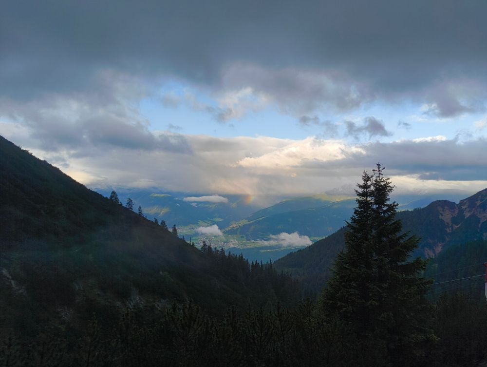 A view down the valley from the mountain hut. A rainbow just peaking out from the clouds and mountains.