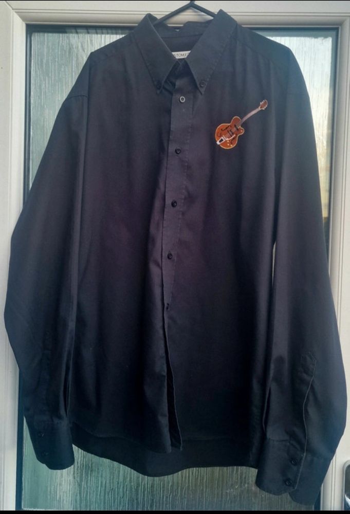 Front of black shirt with small guitar embroidered on chest
