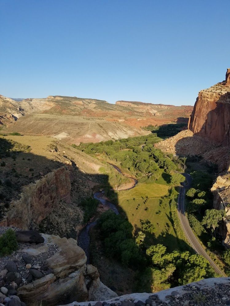 Fremont River valley as morning light hits it, shadows still present, red rock in background.