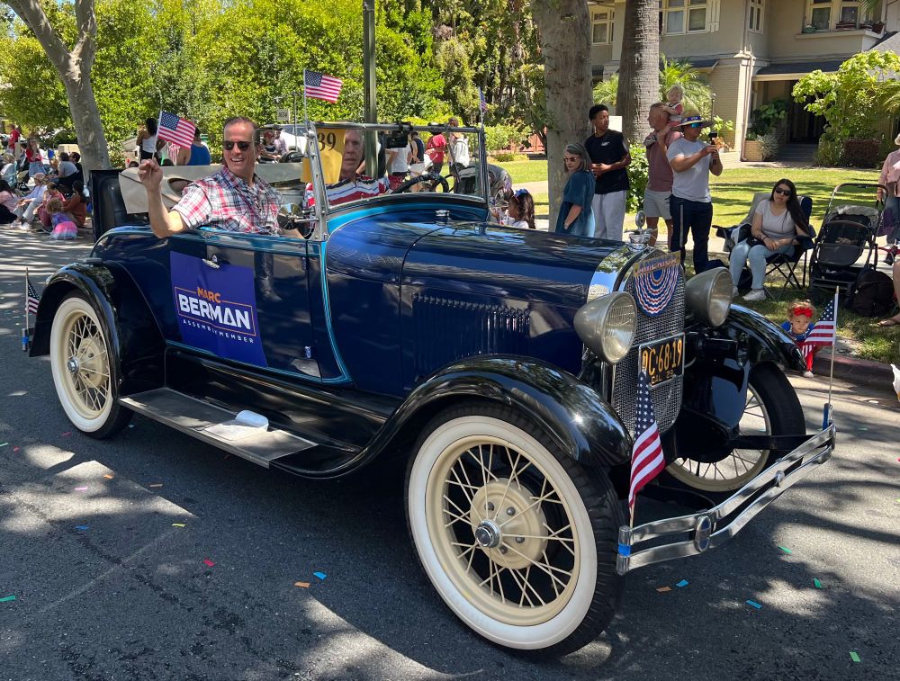 Marc Berman riding in a car at a 4th of July parade. 
