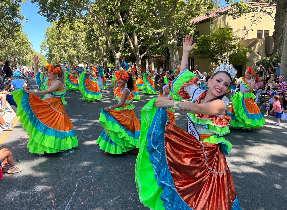 A colorful dance troupe at a 4th of July parade. 