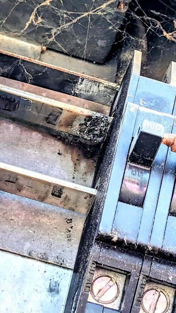 Close-up photo of a heavily corroded Zinsco electrical panel showing a 100-amp circuit breaker partially seated on a deteriorated aluminum bus bar. The contact area beneath the breaker is darkened, pitted, and visibly burned, with surrounding grime and corrosion buildup. Cobwebs and dust are present throughout the panel, suggesting age, neglect, or lack of regular maintenance. The copper screws at the bottom of the breaker appear intact but discolored.

Zinsco panels have a known history of safety issues, particularly related to their aluminum bus bars and poor breaker-to-bus contact, which can lead to overheating, arcing, and failure to trip under load. This image is a textbook example of those risks—clear physical evidence of thermal damage and conductor breakdown at the breaker interface.

It’s the kind of electrical hazard that lurks in forgotten corners of older buildings, quietly turning from an inconvenience into a liability. This photo isn’t just documentation—it’s a compelling case for immediate panel replacement before this corrosion becomes catastrophic.