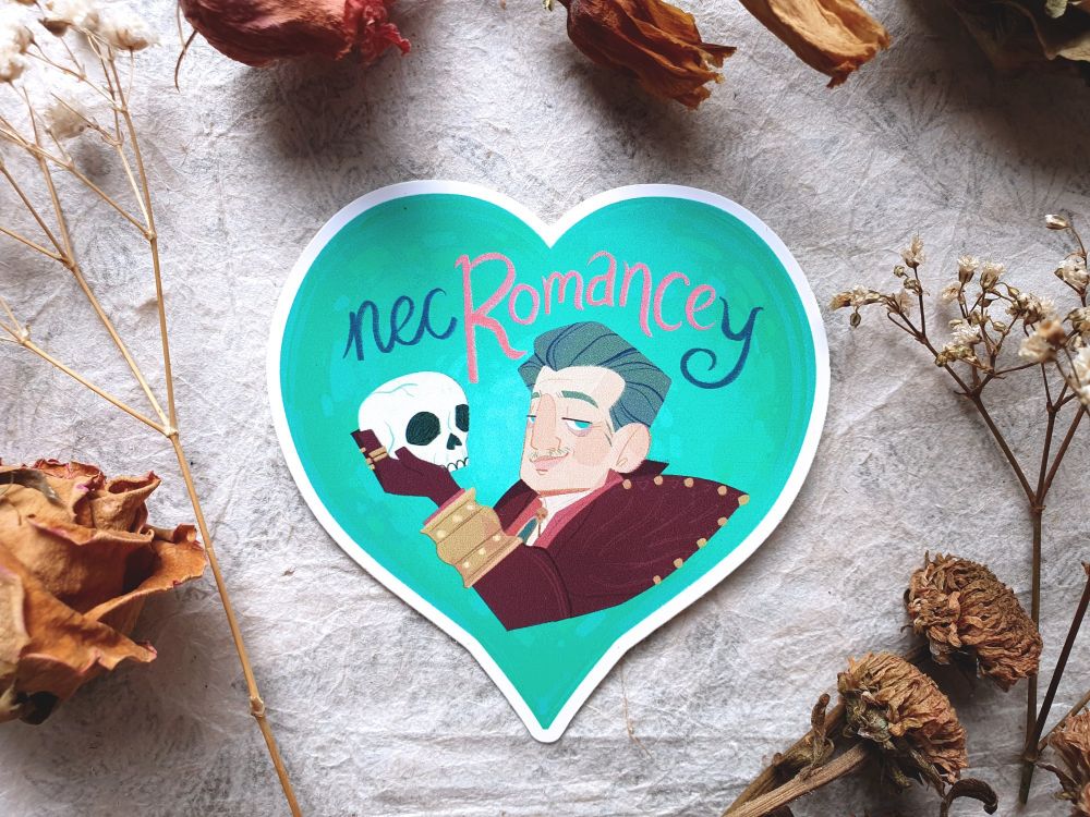 Photo of my Emmrich Volkarin heart-shaped sticker. Emmrich holds a skull and looks at the viewer with a flirty face. It says nec-Romance-y above him.