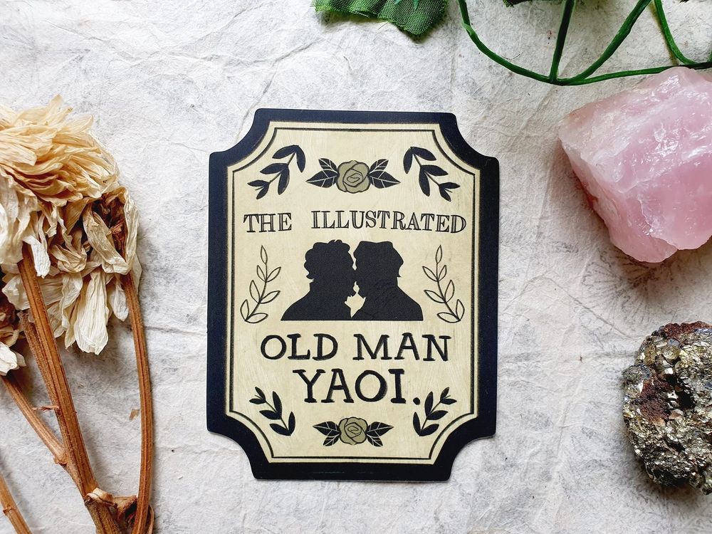 Photo of my Old Man Yaoi sticker. It is inspired by victorian bookplates. It says The Illustrated Old Man Yaoi with a silhouette of two old men about to kiss.