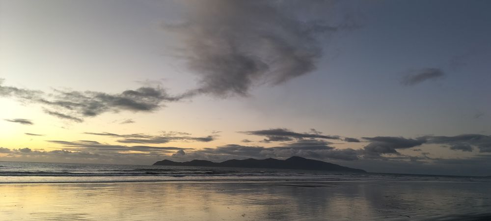 Kapiti island from Paekakariki beach. A hump backed island silhouette against silver and peach sea and sky