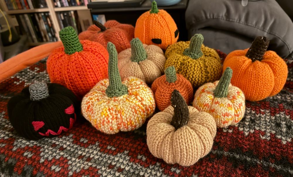 Knitted and crocheted pumpkins in different shades of orange with one black and red jack o’ lantern.