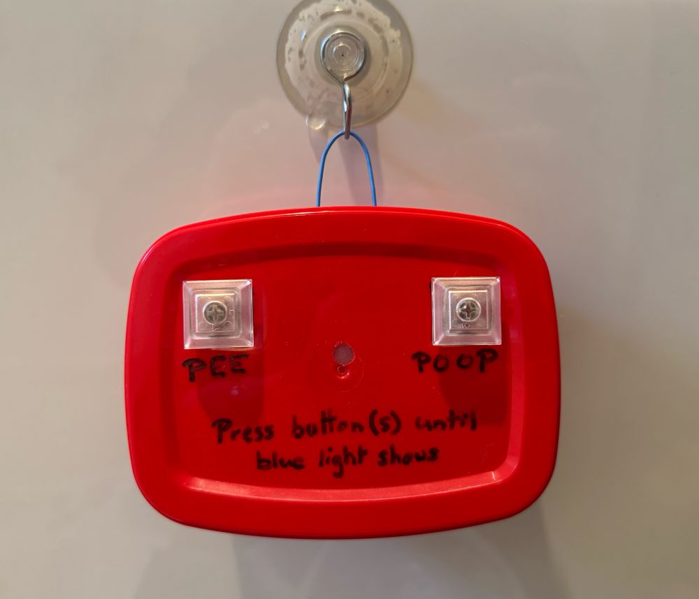 A DIY device with two buttons: Pee and Poop, with instructions to “Press button(s) until blue light shows”