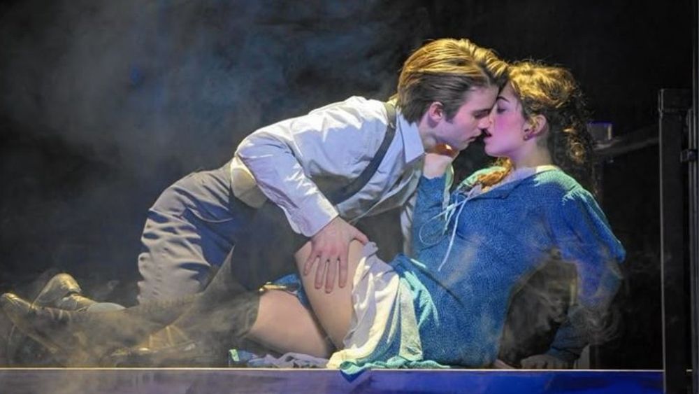 Photo reference of a couple on what looks like a theatre stage. Same pose as in the drawing.