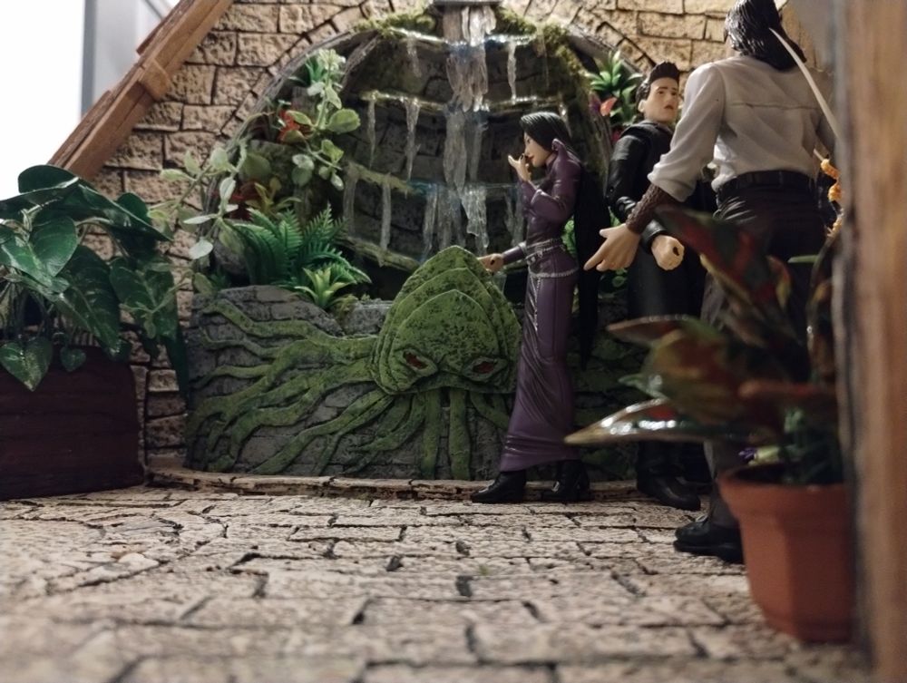5 inch action figures in a faux stone dollhouse room with a large water fountain & plants. 1:12 scale