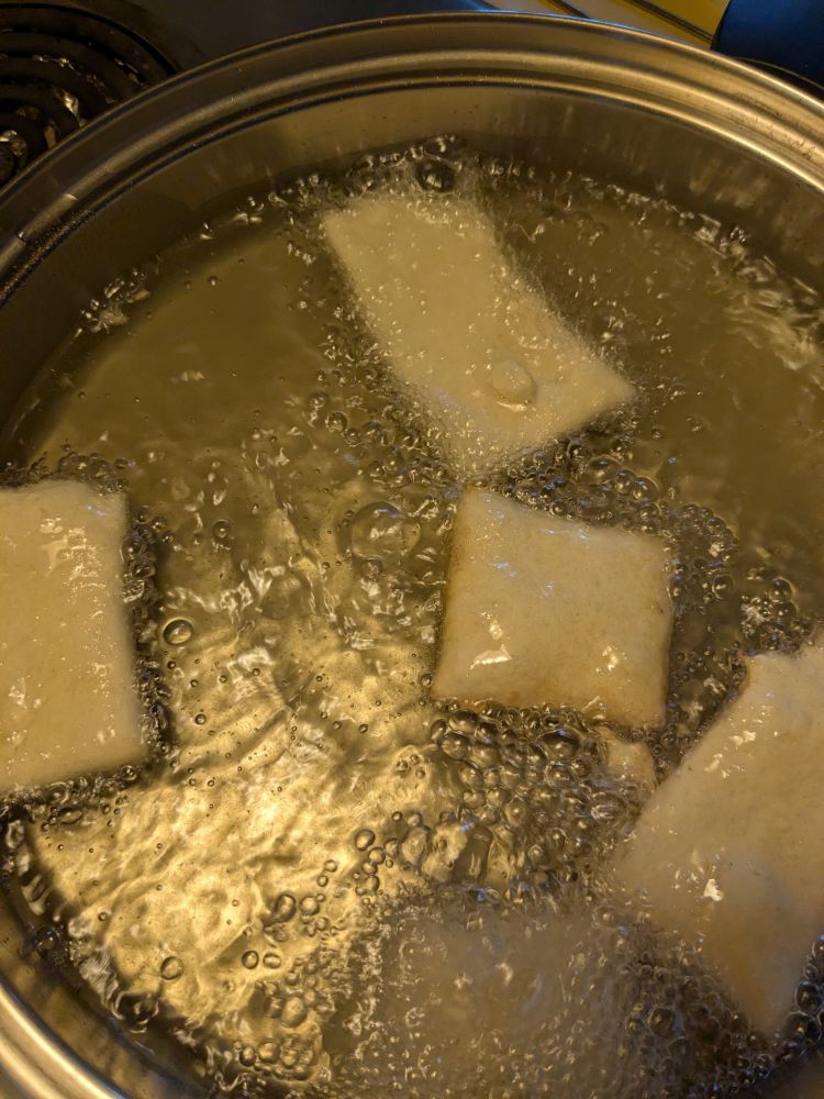 Pieces of beignet frying in a pan.