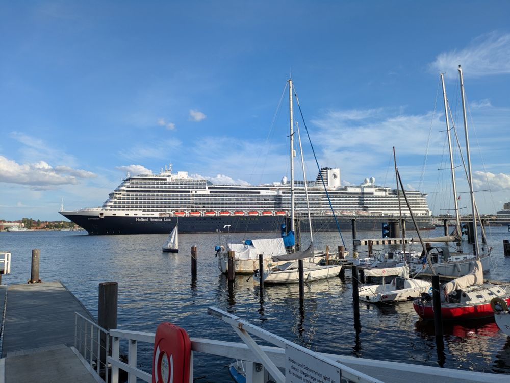 Kreuzfahrer auf der Förde, im Vordergrund Segelboote und ein Steg
