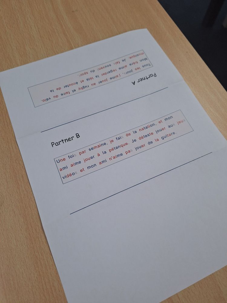 The same paper from image one, flattened on a desk. Partner A and a short text is written in the top third, upside down. In the second third, it says Partner B and a short text. The bottom third is blank. There are lines separating the paper into thirds, to show where you should fold it to create the 'toblerone' shape.