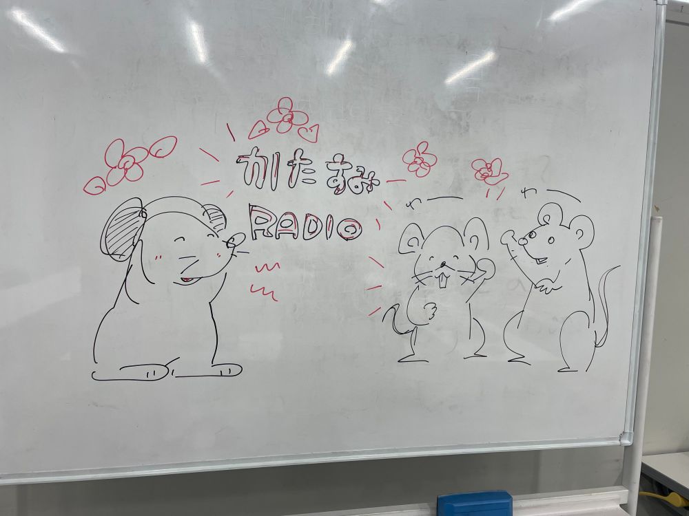 ホワイトボードに書かれたネズミのイラストと、「かたすみRADIO」の文字