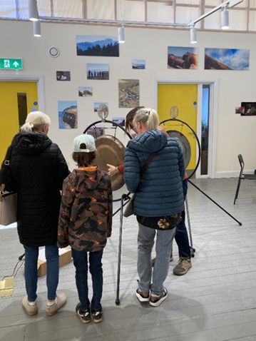 Some visitors at the exhibition. The gong is ‘telling its story’, amplifying recorded sounds along its way, starting at the forge.