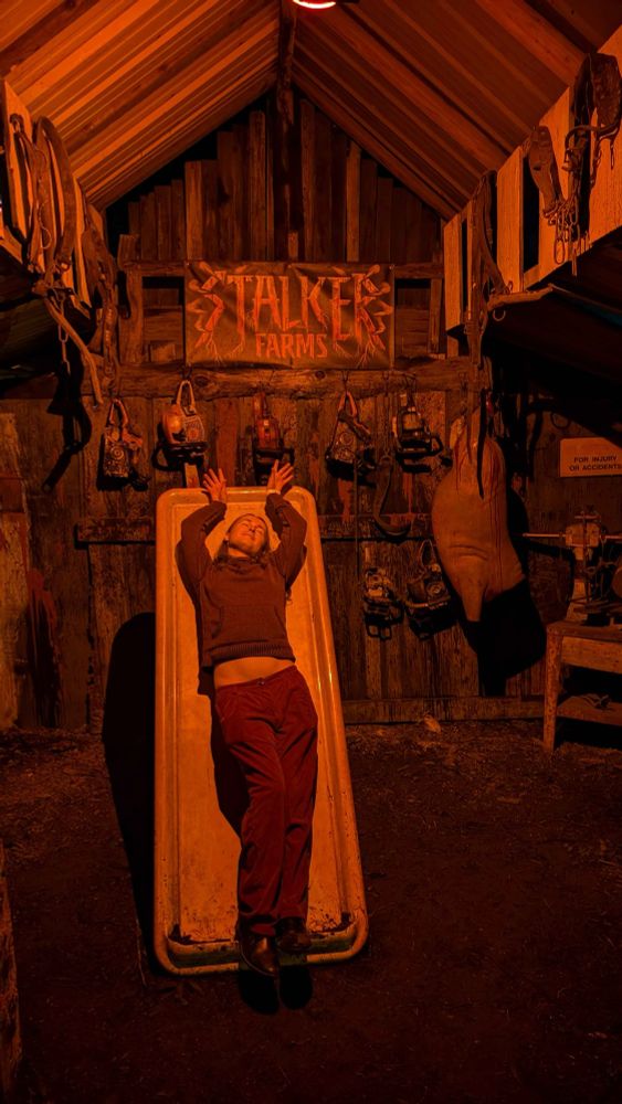 Dressed in red posing on a platter at a haunted house filled with farm-themed horror props
