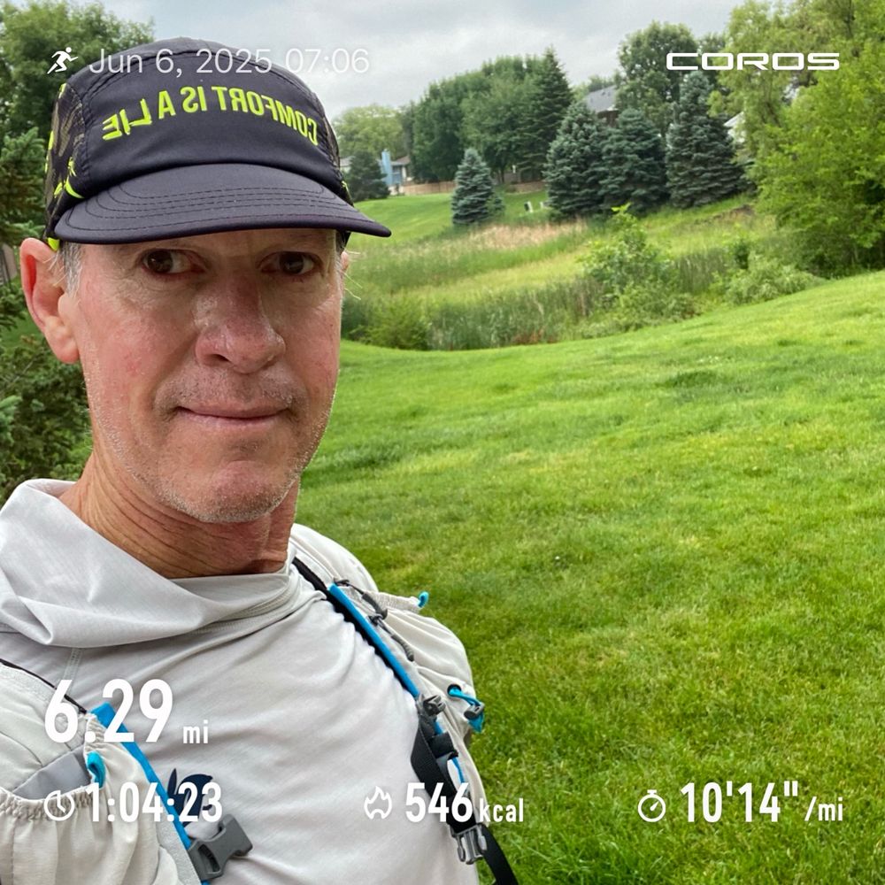 Runner posing before a grassy hill. 