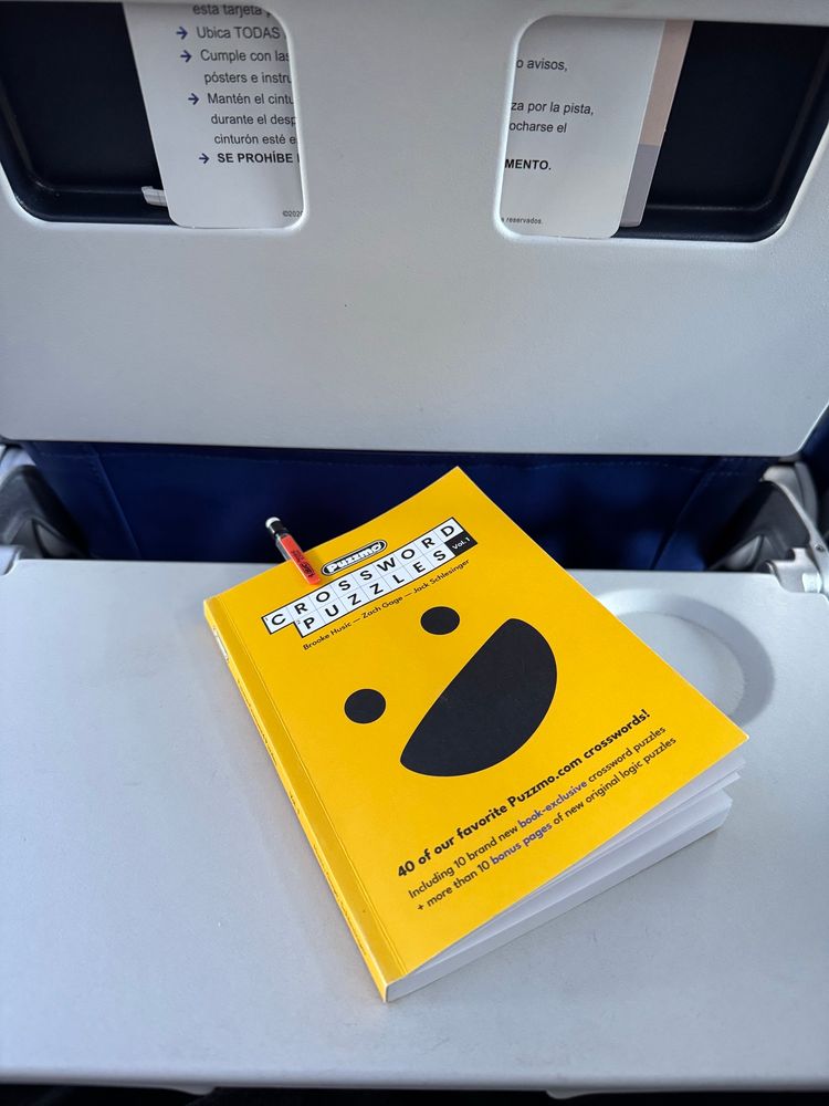 photo of a puzzmo.com crossword book on an airplane tray table