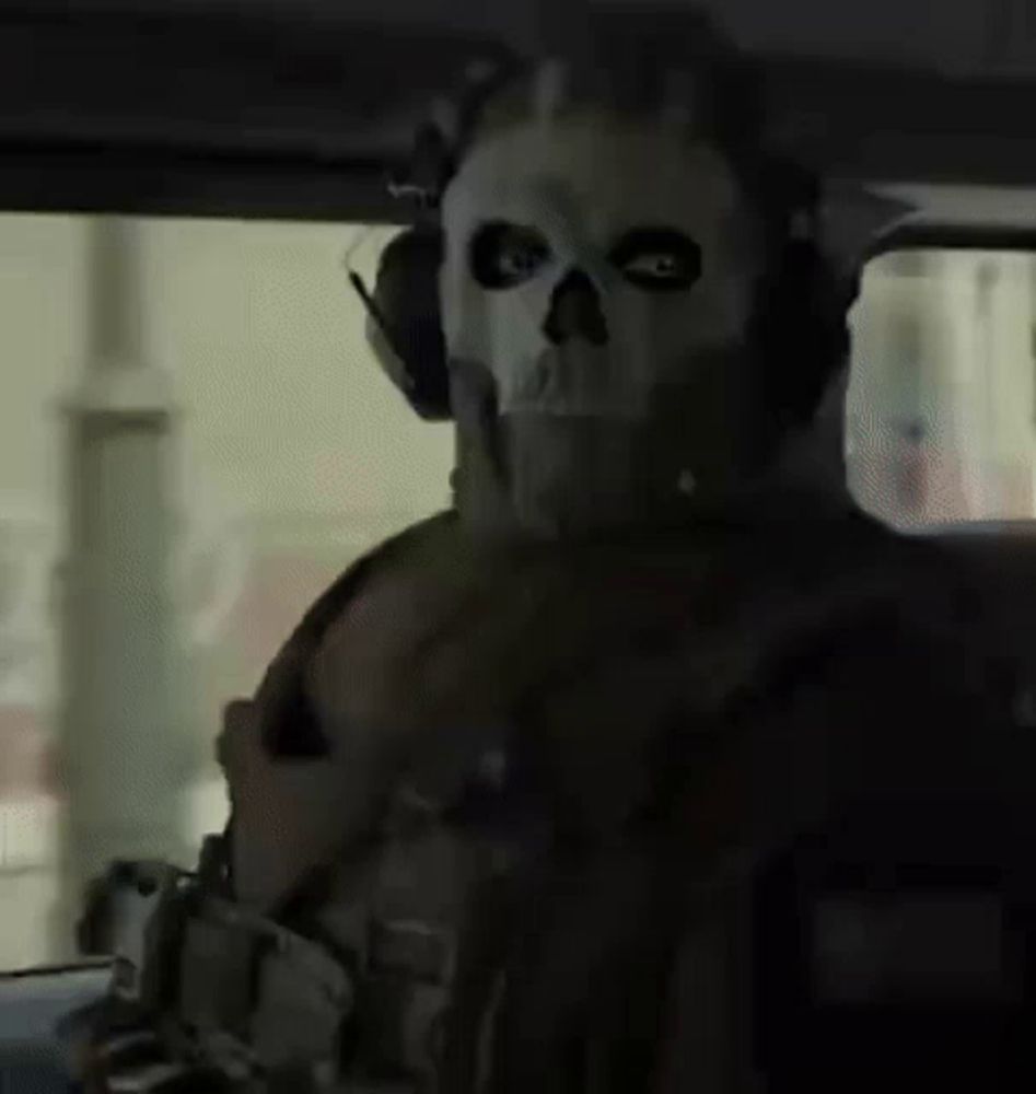 a soldier wearing a skull mask and headphones is sitting in the driver 's seat of a car .