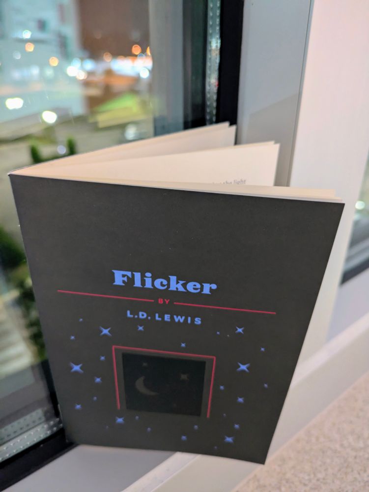 Short story booklet on a windowsill with nighttime street lights outside 