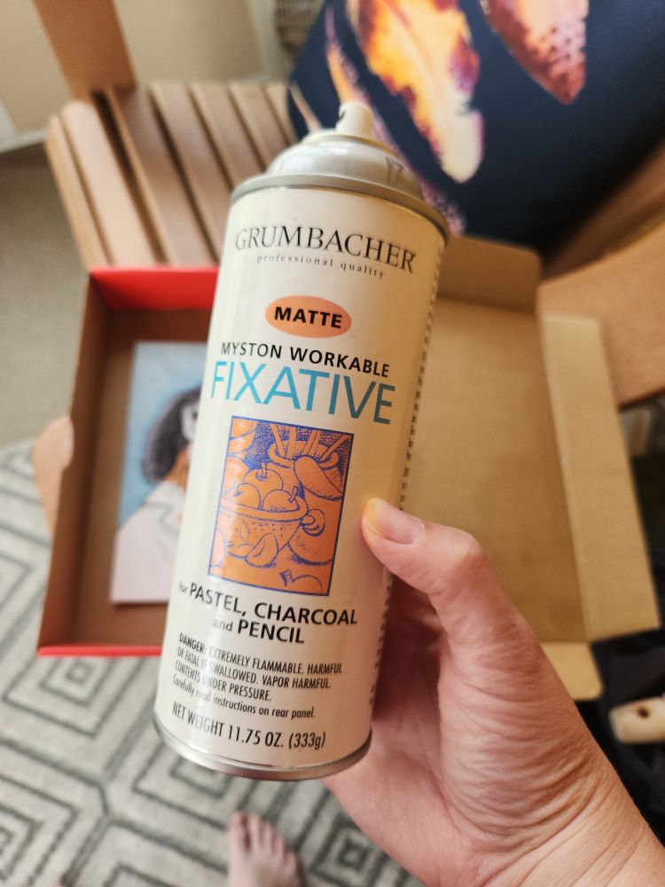 Hand holding a spray can of fixative