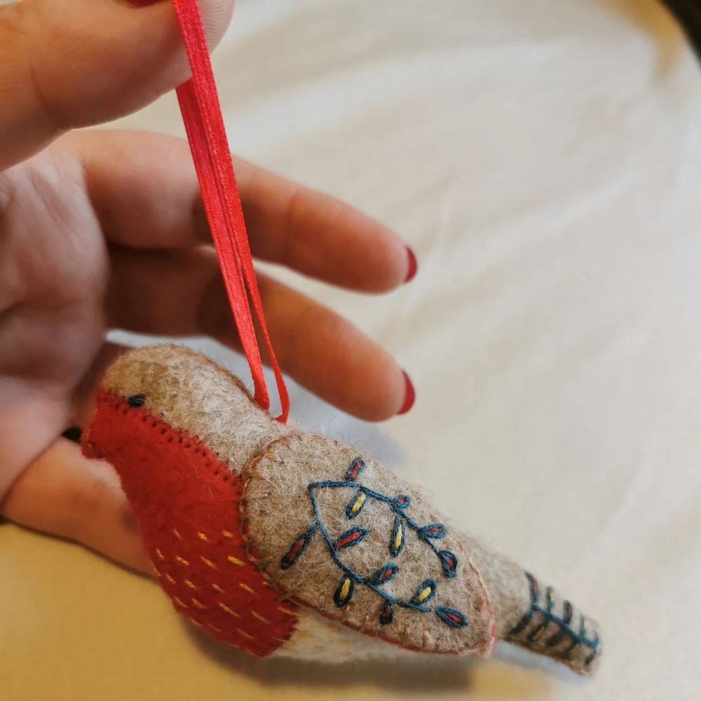 Handmade bird decoration covered in embroidery. The belly looks like a strawberry which makes me laugh. The winds and tail look like holiday lights which was not what the kit intended but I absolutely ignored their instructions on what colours to do the wing embroidery in)