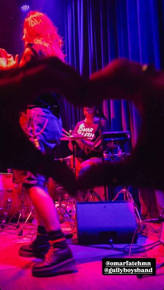 Someone makes a heart with their hands around Gully Boys drummer, Nadi, who is wearing an Omar Fateh for Minneapolis Mayor t-shirt.