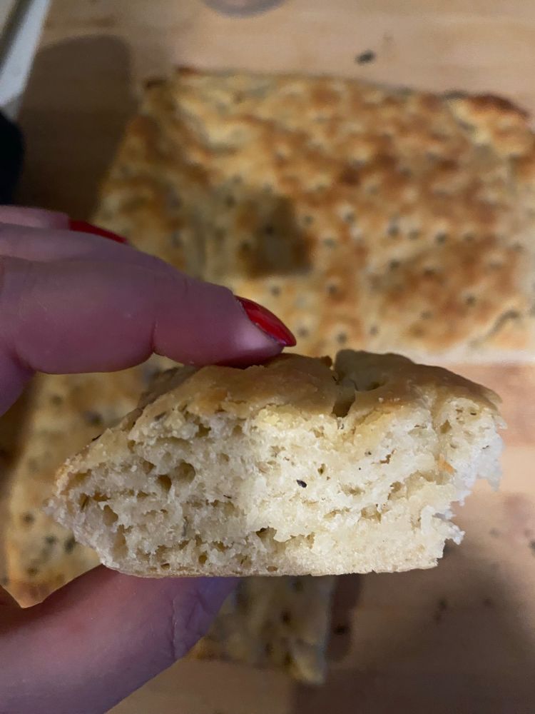 Foccacia maison : part en gros plan et la foccacia entière derrière 