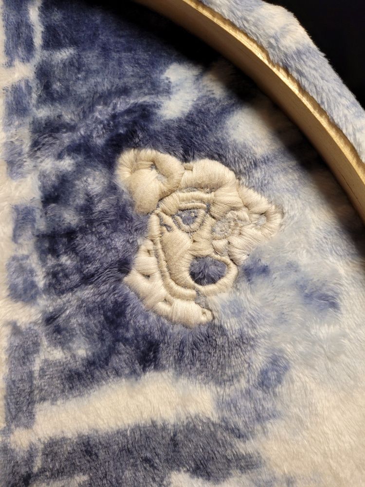 A close-up photo of a work in progress art piece. The art piece is an embroidery of Perdita (Perdy) from Disney's 101 Dalmatians.