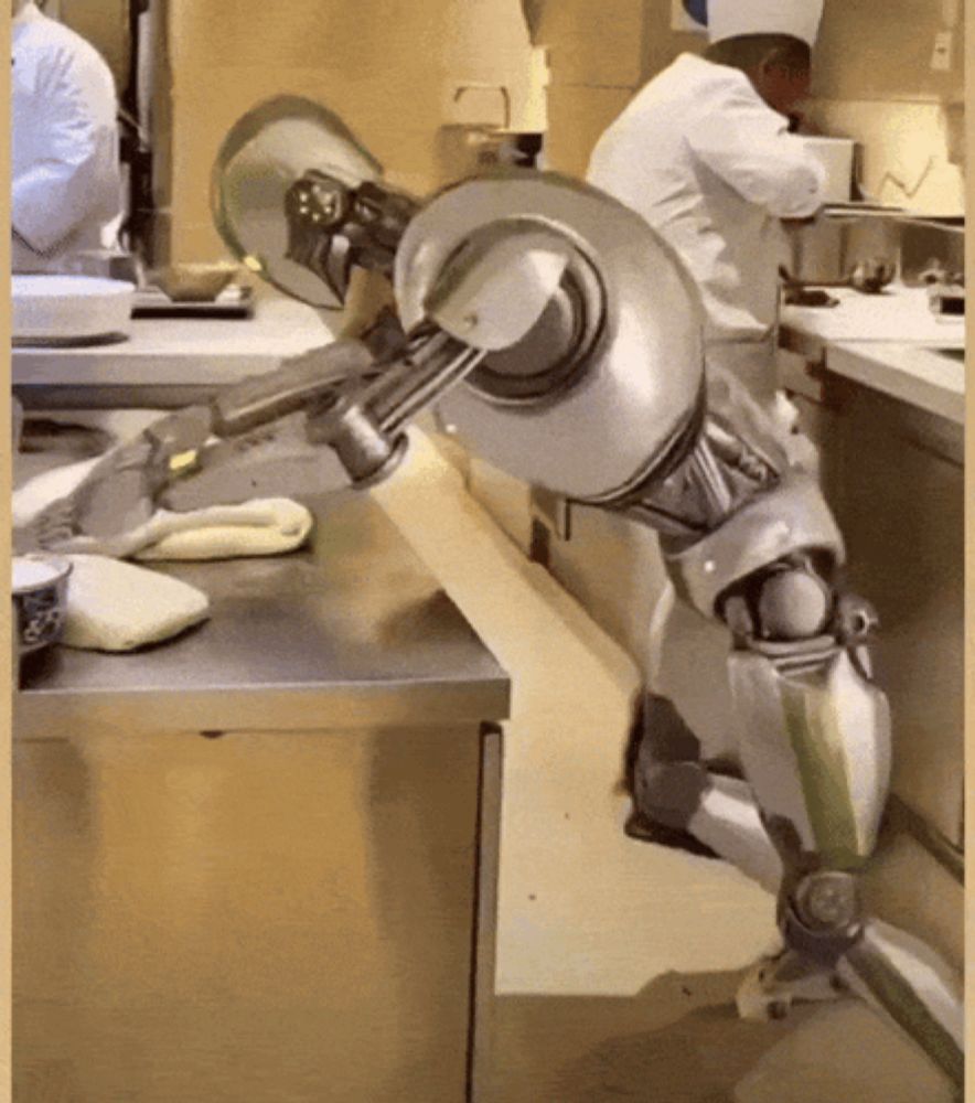 a man in a chef 's hat is standing behind a robotic arm