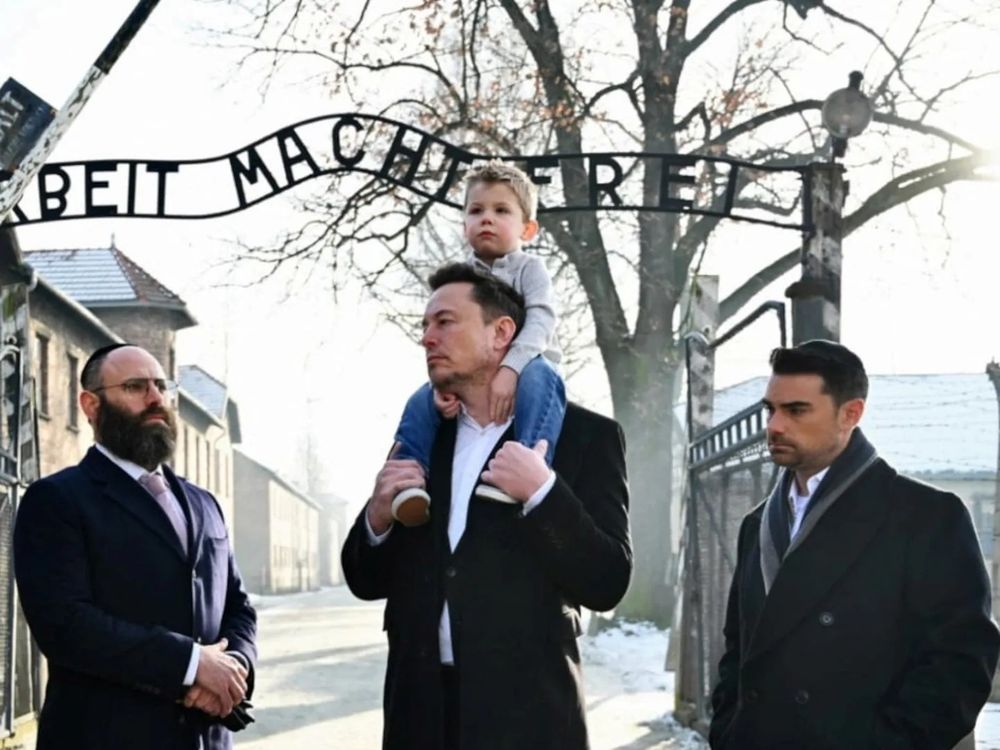 Elon Musk with a child on his shoulders at Auschwitz. 